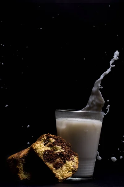 Mjölk glas stänk med kaka dessert isolerad på svart bakgrund — Stockfoto