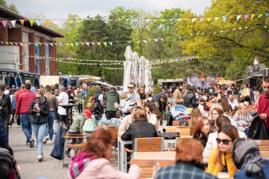 Bükreş, Romanya: 21.04.2019 - Sokak Yemekleri Kamyonu festivali - Pazar günü parkta düzenlenen yemek festivalinde masalarında oturup yemek yiyen insanlar