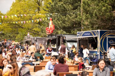 Bükreş, Romanya: 21.04.2019 - Sokak Yemekleri Kamyonu festivali - Pazar günü parkta düzenlenen yemek festivalinde masalarında oturup yemek yiyen insanlar