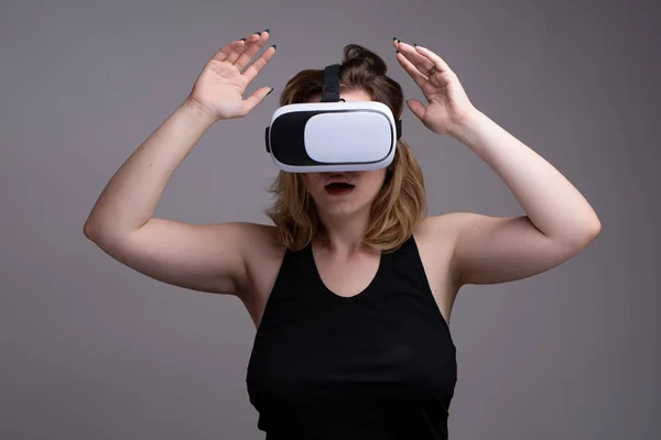 Female using VR gear is holding her hands up as displaying a shocked expression