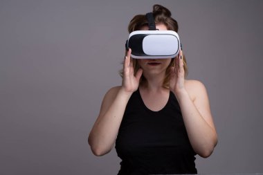VR Google 'a dokunan genç bir kadın. Gri arkaplanda izole