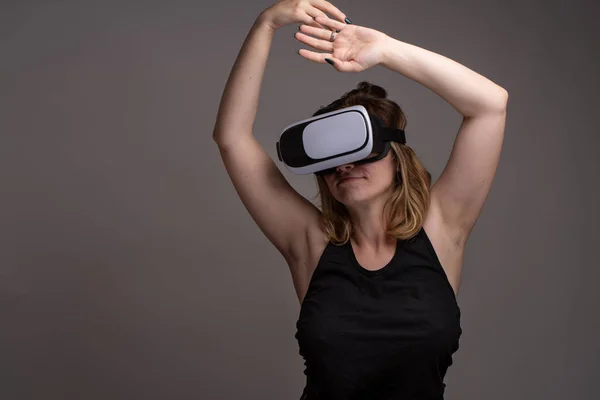 Young female using VR gear is dancing and stretching hands