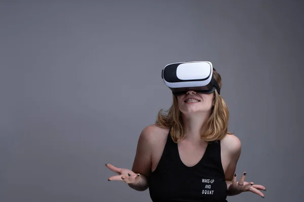 Female using VR gear is having fun and displaying a dont know attitude