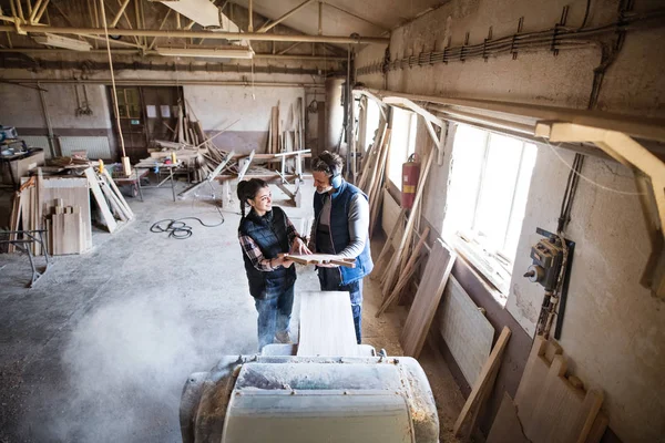 Man and woman workers in the carpentry workshop holding wood. — Stock Photo, Image