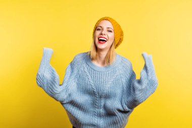 Studio sarı bir arka plan üzerine yün şapka olan güzel bir kadın portresi.