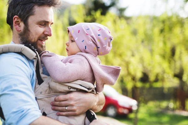 En far med sin toddler dotter i en bärsele utanför på en våren promenad. — Stockfoto