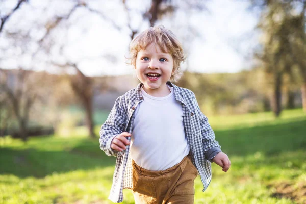 Glada barnet pojke kör utanför i vår natur. — Stockfoto