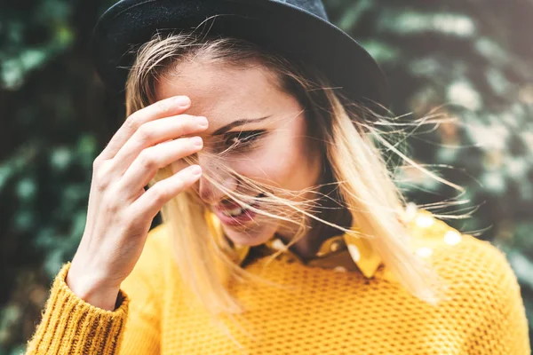 Mujer joven con sombrero negro de pie sobre un fondo verde en primavera soleada . —  Fotos de Stock