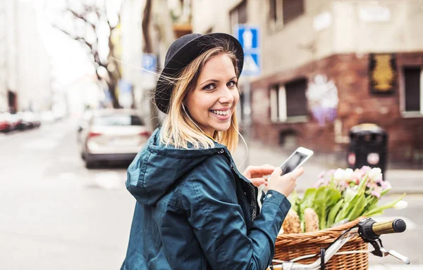Młoda kobieta z roweru i smartfon w mieście sunny wiosna. — Zdjęcie stockowe