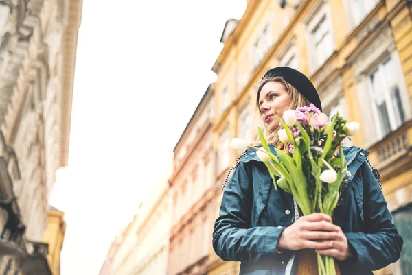 Jonge vrouw met bloemen in zonnige lente stad. — Stockfoto