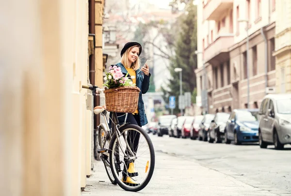 自転車や日当たりの良い温泉街でスマート フォンを持つ若い女性. — ストック写真