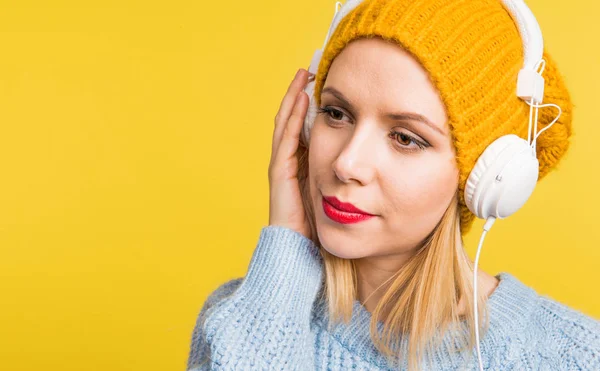 Portrait of a young beautiful woman with headphones in studio on a yellow background. — Stock Photo, Image