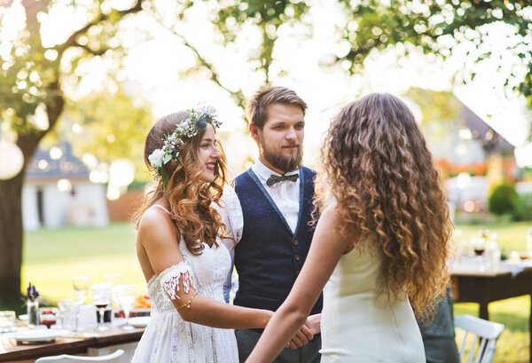 Young girl congratulating bride and groom at wedding reception in the backyard.