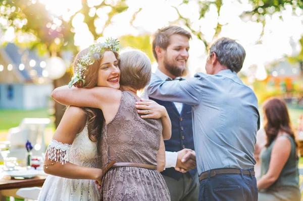 Gäste gratulieren Braut und Bräutigam bei Hochzeitsempfang draußen im Hinterhof. — Stockfoto
