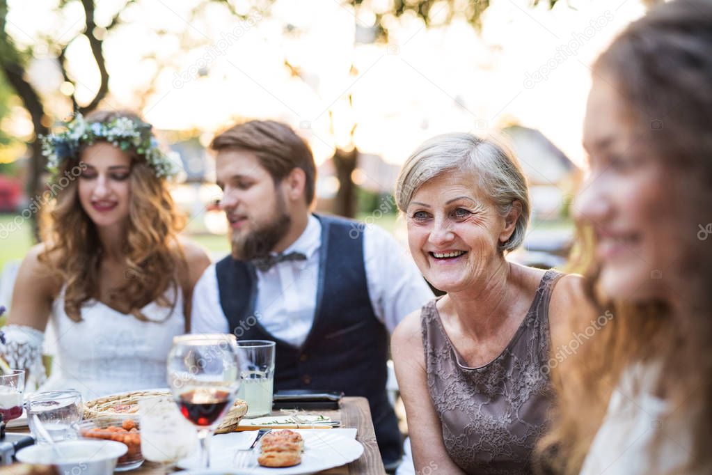 Bride and groom with guests at wedding reception outside in the backyard.