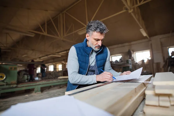 Ένας άνδρας εργαζόμενος στο εργαστήριο ξυλουργικής, κάνοντας σχέδια. — Φωτογραφία Αρχείου