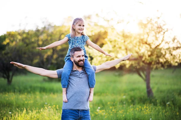 Vater gibt kleiner Tochter Huckepack-Fahrt in der Frühlingsnatur. — Stockfoto