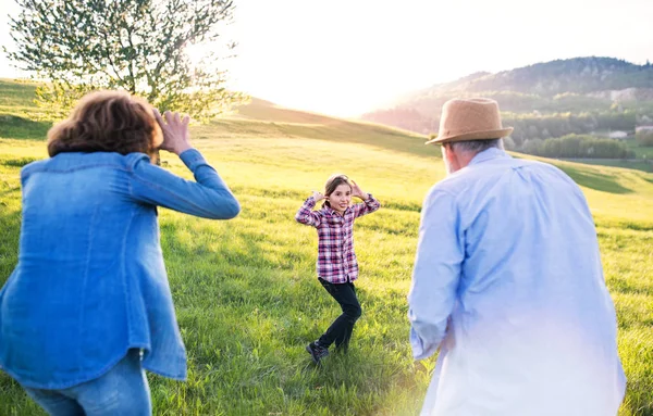 Une petite fille avec ses grands-parents seniors s'amuser dehors dans la nature . — Photo