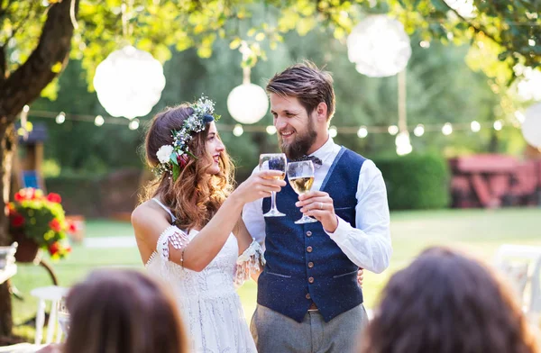 Nevěsta a ženich hosty na svatební hostinu venku v zahradě. — Stock fotografie
