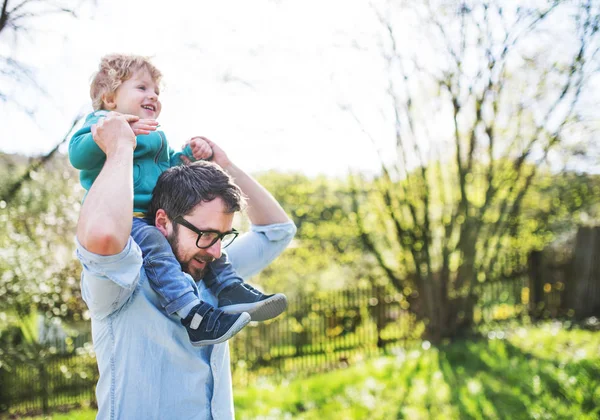 Otec se synem batole venku v jarní přírodě. — Stock fotografie