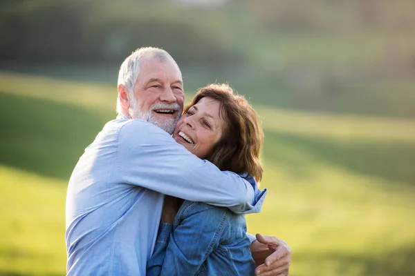 Seniorenpaar umarmt sich draußen in frühlingshafter Natur. — Stockfoto