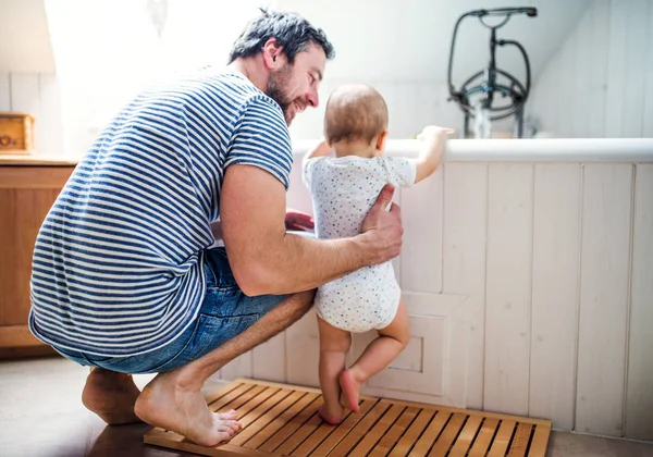 Padre con un niño pequeño en casa de pie junto a la bañera en el baño . — Foto de Stock