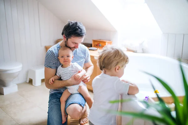 Padre con dos niños pequeños preparándose para el baño en el baño en casa . — Foto de Stock