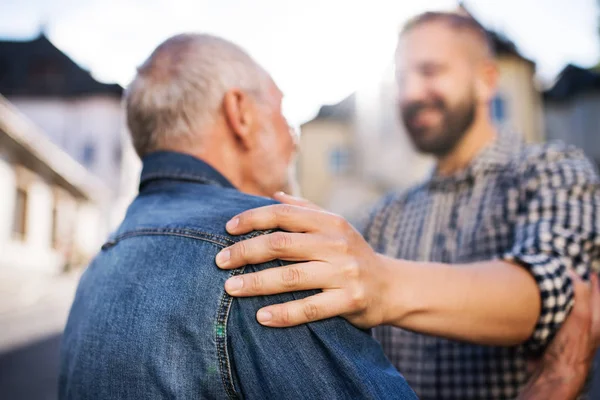 Un figlio hipster adulto con padre anziano in una passeggiata in città . — Foto Stock