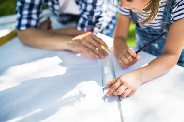 Padre con una piccola figlia fuori, progettando una casetta per uccelli in legno . — Foto Stock