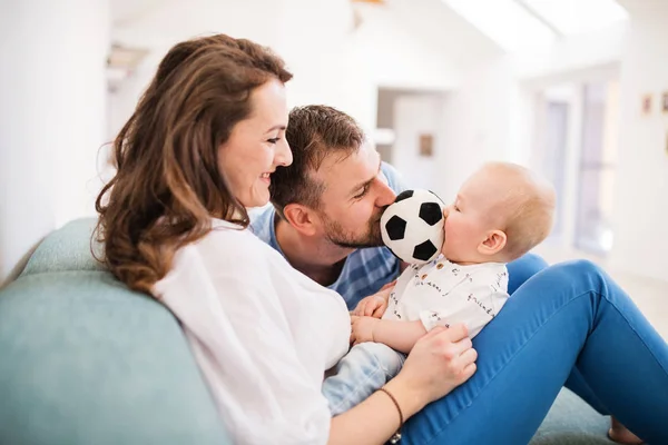 Kanepede oturan genç aile ile evde, erkek bir bebek. — Stok fotoğraf