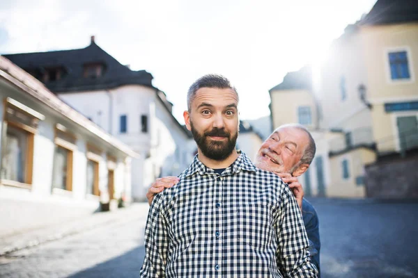 Un figlio hipster adulto con padre anziano in una passeggiata in città . — Foto Stock