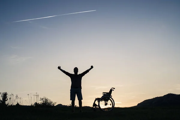 Un jeune homme debout en fauteuil roulant dans la nature le soir . — Photo