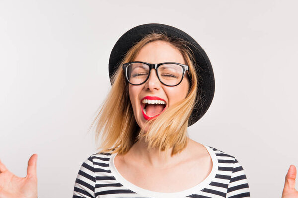 Портрет молодой женщины в черной шляпе, кричащей в студии
.