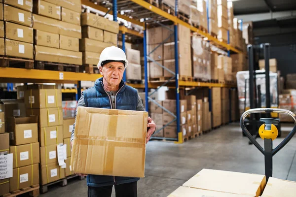 Hombre mayor trabajador de almacén descargando cajas de una transpaleta . — Foto de Stock