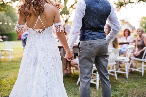 Mariée méconnaissable et marié avec des invités à la réception de mariage à l'extérieur dans la cour arrière . — Photo