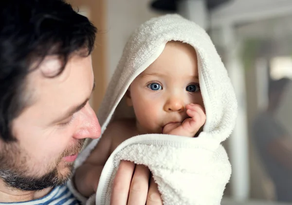 Père avec un enfant en bas âge enveloppé dans une serviette dans une salle de bain à la maison . — Photo