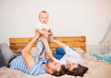 Yatakta yatarken genç aile ile evde, erkek bir bebek.