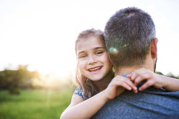 Pai segurando uma pequena filha na natureza primavera ao pôr do sol . — Fotografia de Stock