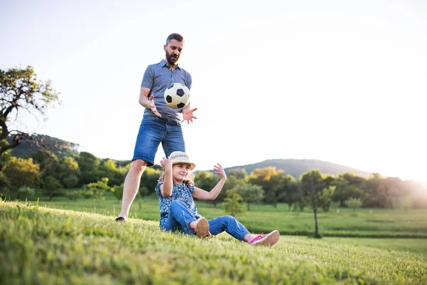Padre con una piccola figlia che gioca con una palla nella natura primaverile . — Foto Stock