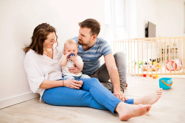 Katta oturan genç aile ile evde, erkek bir bebek. — Stok fotoğraf