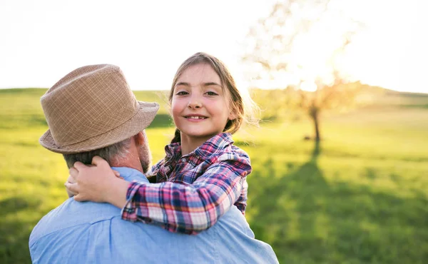 A small girl with grandfather outside in spring nature, having fun. — Stock Photo, Image
