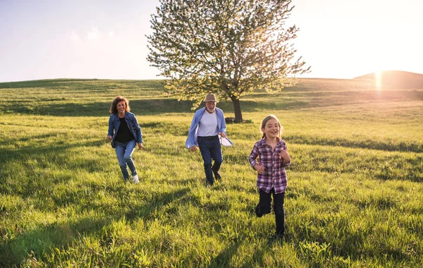 Une petite fille avec ses grands-parents aînés jouant dehors dans la nature . — Photo