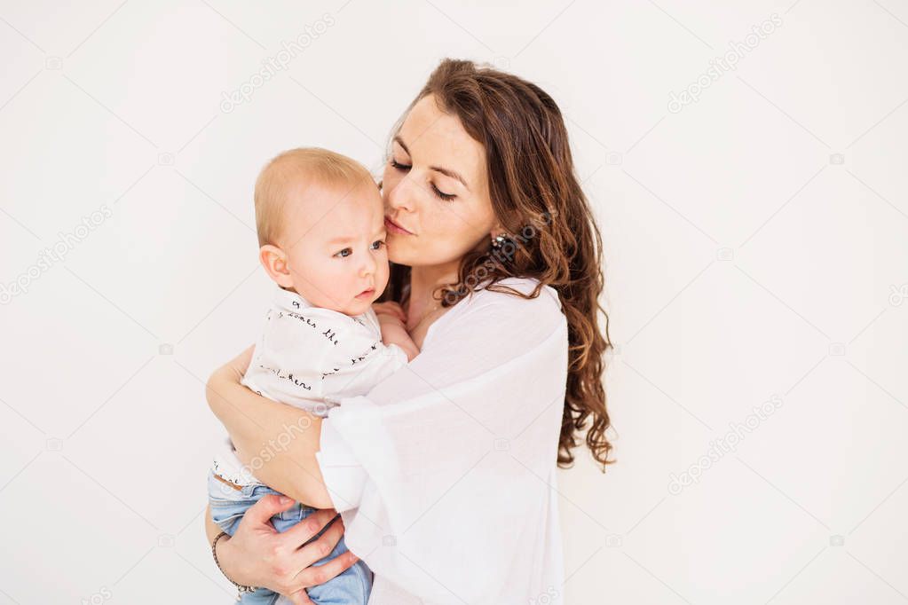 Portrait of a young mother kissing her baby son at home. Copy space.