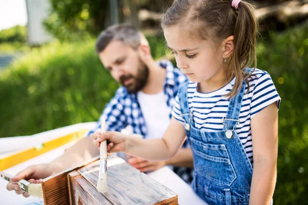 Padre con una piccola figlia fuori, dipingendo casetta di legno per uccelli . — Foto Stock