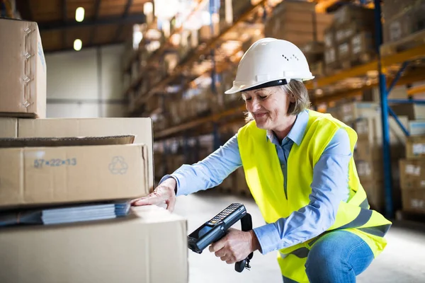 Trabajadora de almacén senior que trabaja con escáner de código de barras . — Foto de Stock