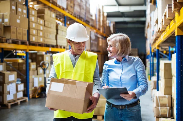 Senior vrouw manager en man werknemer werkt in een magazijn. — Stockfoto