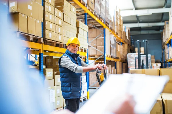 Senior vrouw manager en man werknemer werkt in een magazijn. — Stockfoto