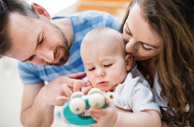 Genç aile ve bir oyuncakla evde erkek bir bebek. Yakın çekim.