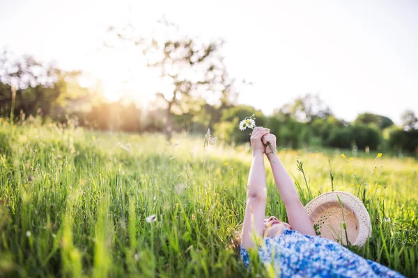 En liten flicka liggande på gräset i vår natur. Kopiera utrymme. — Stockfoto