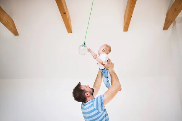 Młody ojciec trzymający syna baby pod sufitem w domu. — Zdjęcie stockowe